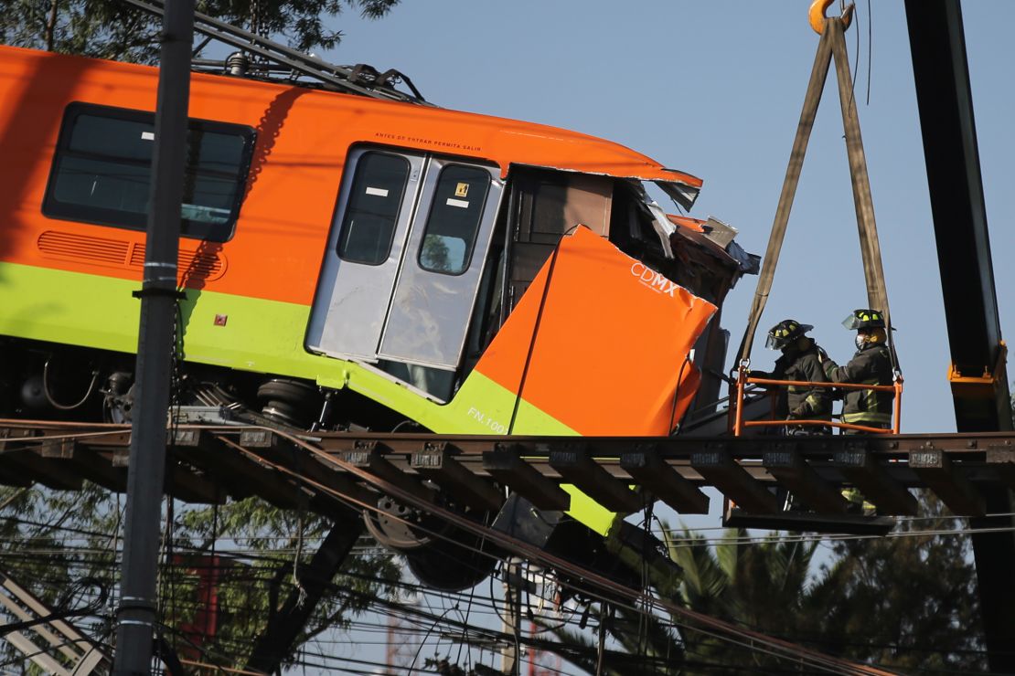 Firefighters work to lower to the ground a subway car dangling from a collapsed elevated section of the metro, in Mexico City, Tuesday, May 4, 2021. 