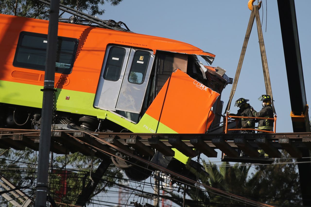 Firefighters work to lower a subway car that was dangling from the elevated overpass.