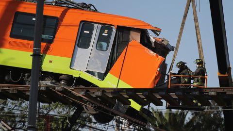 Firefighters work to lower to the ground a subway car dangling from a collapsed elevated section of the metro, in Mexico City, Tuesday, May 4, 2021. 
