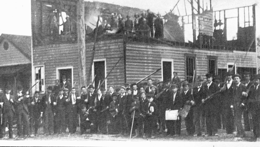 White supremacists gather outside the scorched remains of Wilmington's Daily Record newspaper building following the 1898 massacre.