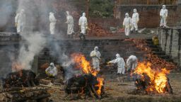 Nepalese men in personal protective suits cremate the bodies of COVID-19 victims while others extend the crematorium as the number of deaths rise near Pashupatinath temple in Kathmandu, Nepal, Wednesday, May 5, 2021. Authorities extended lockdown in the capital Kathmandu and surrounding districts by another week on Wednesday as the Himalayan nation recorded the highest COVID-19 daily infection and death. (AP Photo/Niranjan Shrestha)