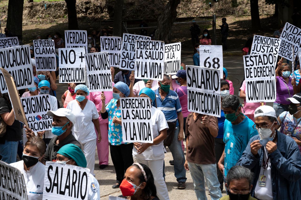 Health workers carry signs while participating in a protest outside a hospital in Caracas, Venezuela, on May 1. During the protest, which was part of International Workers' Day, they demanded better wages and working conditions as well as mass vaccinations against Covid-19.