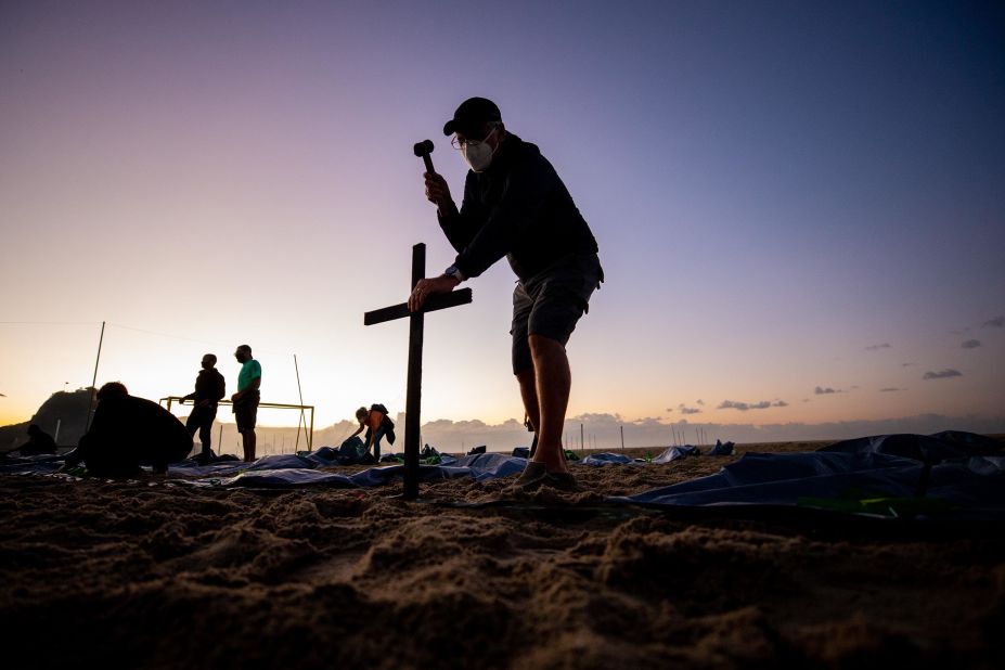 A member of the group Rio de la Paz places a cross at Rio de Janeiro's Copacabana Beach on April 30. It was in preparation for an event marking Brazil's Covid-19 death toll, which had reached 400,000.