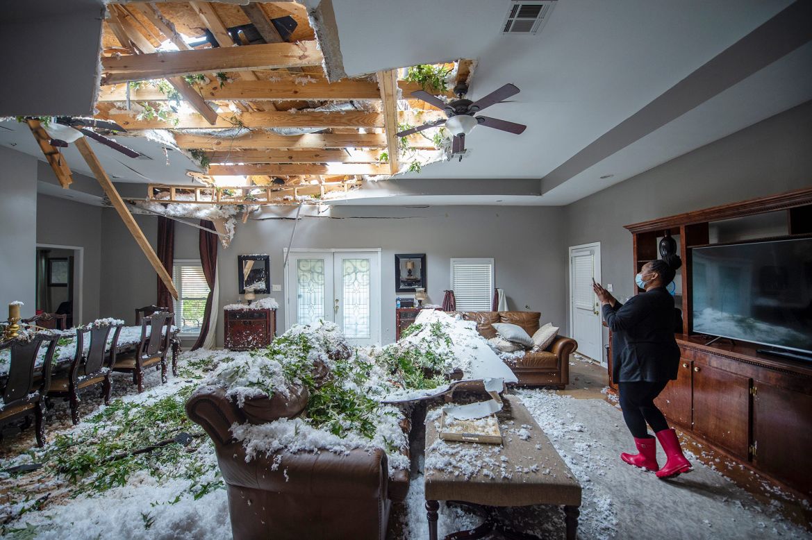 A woman takes photos of her mother's home after a tree landed on the roof in Jackson, Mississippi. Tornadoes touched down in Hinds and Rankin counties on Tuesday, May 4, according to the National Weather Service.