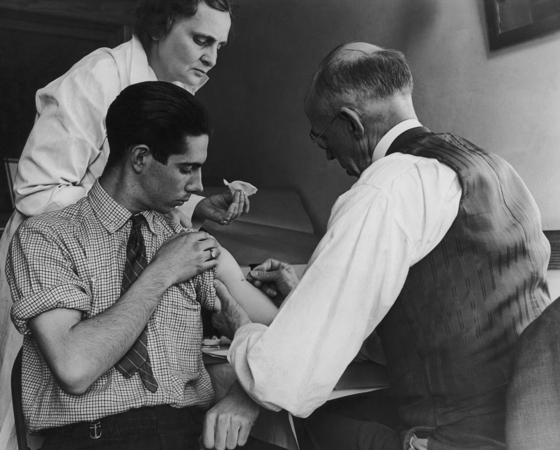 A school doctor and nurse deliver a smallpox vaccination in 1938 to a teen in Gasport, New York.