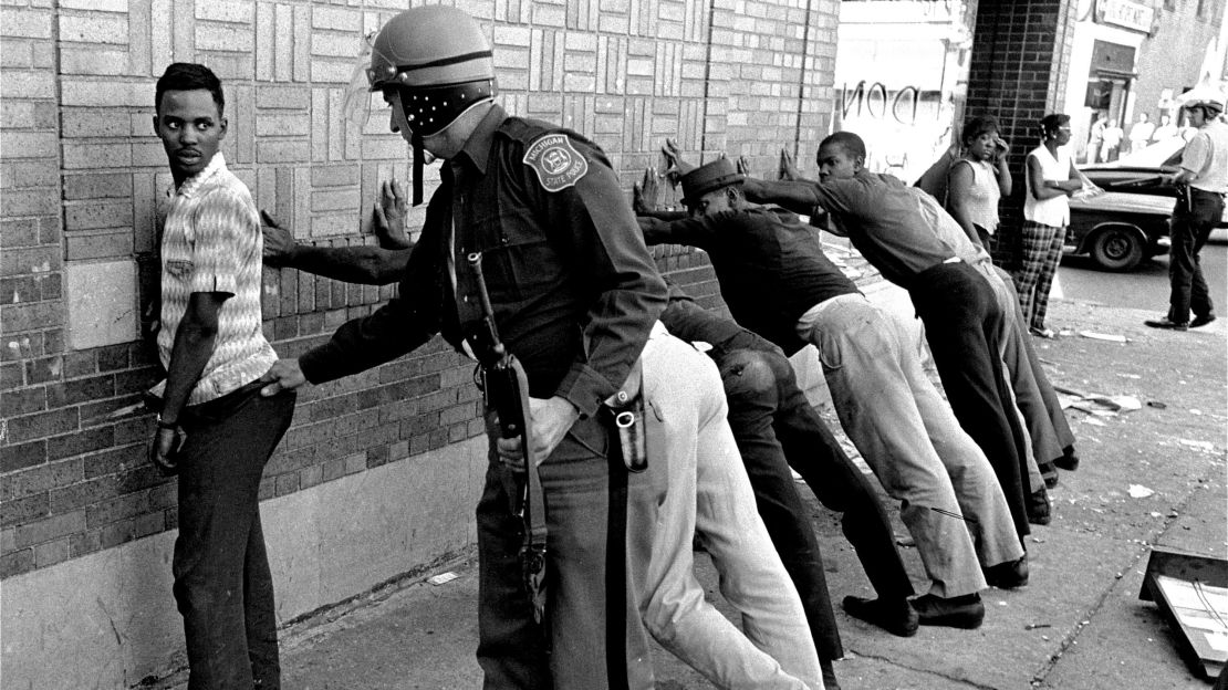 A Michigan State police officer searches a youth on Detroit's 12th Street where looting took place in the 1960s.