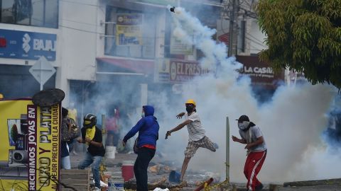 A demonstrator throws a tear gas canister at riot police officers in Cali, Colombia, on May 3, 2021.