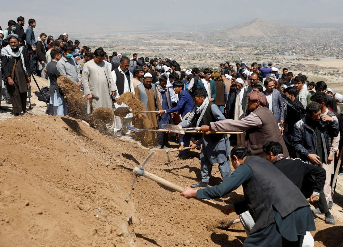 Men dig graves for the victims of Saturday's explosion during a mass funeral ceremony in Kabul.
