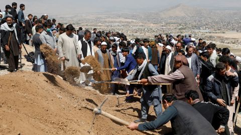 Men dig graves for the victims of Saturday's explosion during a mass funeral ceremony in Kabul.