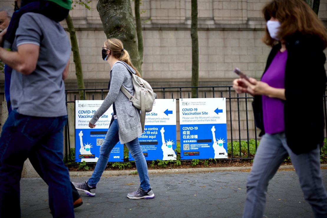 Pedestrians pass in front of Covid-19 vaccination site signs in New York on April 30.