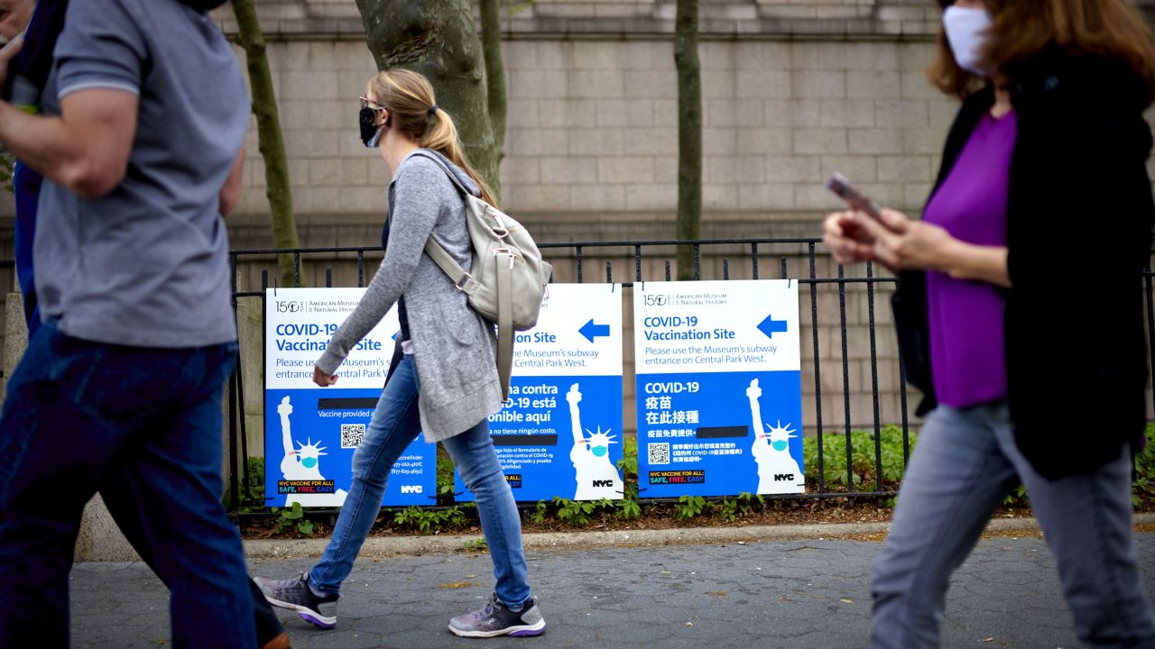 Pedestrians pass in front of Covid-19 vaccination site signs in New York on April 30.