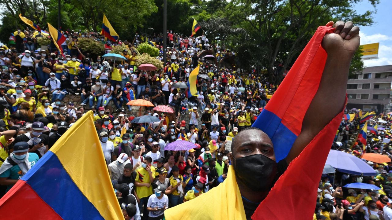 People hold a sign reading Democracy is not in quarantine during protest against a tax reform bill they say will leave them poorer as the country battles its deadliest phase yet of the coronavirus pandemic, in Cali, Colombia, on May 1, 2021. - Colombian President Ivan Duque caved in on April 30 to widespread anger and said he would overhaul the proposed tax reform. Duque announced he was shelving clauses that would lower the income tax threshold to broaden the tax base and raise value-added taxes on goods and services. (Photo by Luis ROBAYO / AFP) (Photo by LUIS ROBAYO/AFP via Getty Images)