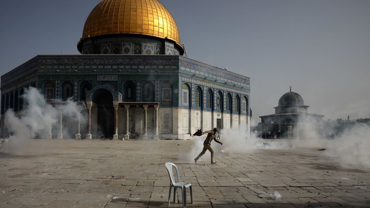 A Palestinian man runs from tear gas during clashes with Israeli security forces in front of the Dome of the Rock on Monday. 