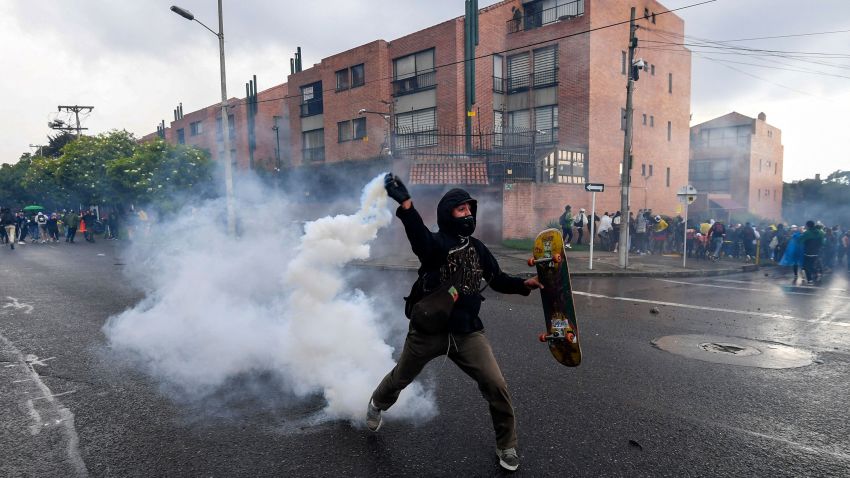 A man returns a tear gas canister at police during a demostration outside Colombian President Ivan Duque's house in Bogota on May 1, 2021. - Thousands of people demonstrated Saturday for the fourth consecutive day in Colombia to demand the withdrawal of a tax reform that, they claim, punishes the middle class in the midst of the pandemic. (Photo by Juan BARRETO / AFP) (Photo by JUAN BARRETO/AFP via Getty Images)