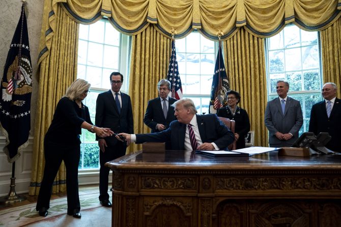 Trump hands a pen to Cheney after <a href="index.php?page=&url=https%3A%2F%2Fwww.cnn.com%2F2020%2F04%2F23%2Fpolitics%2Fhouse-vote-small-business-aid-vote%2Findex.html" target="_blank">signing a coronavirus relief package</a> in April 2020.