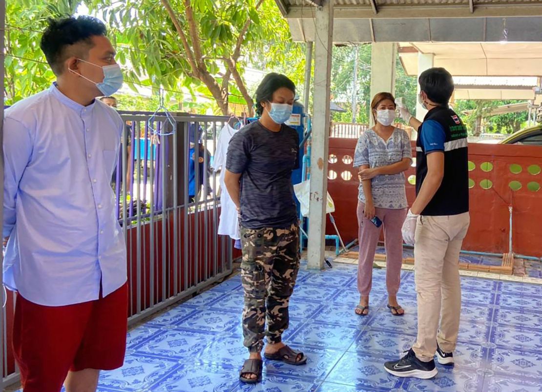 In this photo released by the San Sai District Administrative Office, a Thai officer checks the temperature of journalists working for Democratic Voice of Burma, at San Sai District in Chiang Mai province north of Thailand Sunday, May 9, 2021.