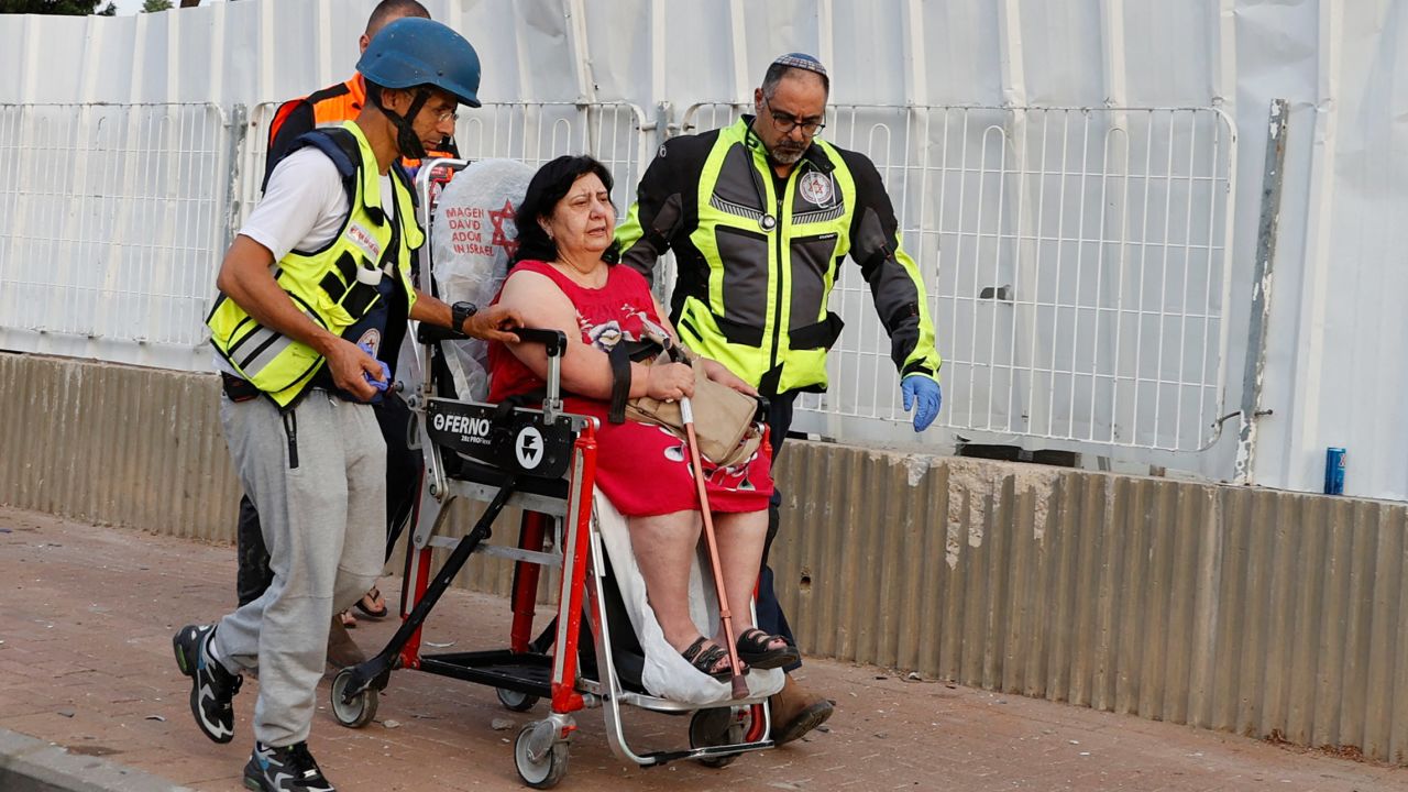 Israeli rescue teams evacuate a woman from a residential neighborhood in Ashkelon Tuesday after rockets were fired from Gaza towards Israel overnight amid spiralling violence.