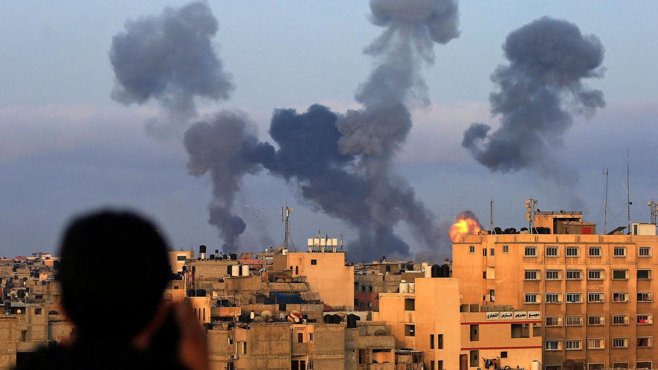 A Palestinian boy watches smoke billowing from buildings during Israeli airstrikes on the southern Gaza region of Khan Yunis, on May 11, 2021