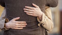 adult couple standing on street and hugging. closeup of woman hands hugging man outside
