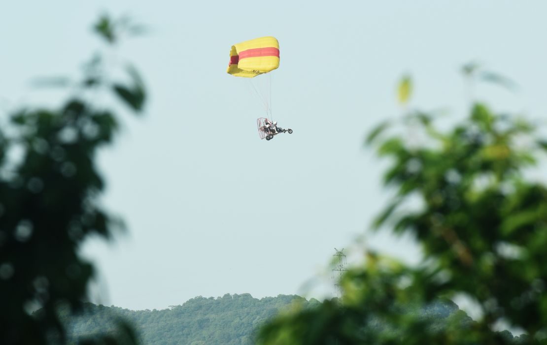 A staff member uses a powered parachute to search for an escaped leopard in the mountains near Hejia Village in the West Lake District of Hangzhou, capital of east China's Zhejiang Province, May 9, 2021.