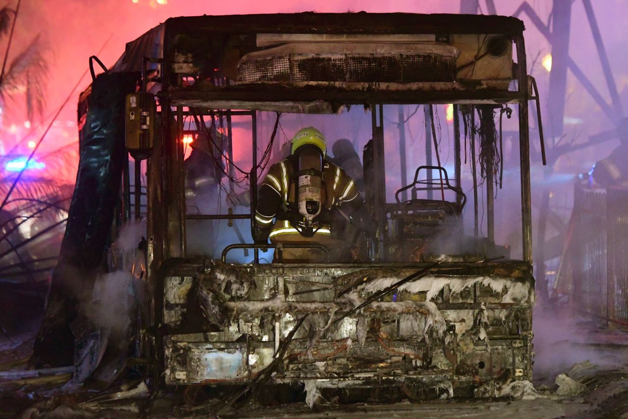 An Israeli firefighter extinguishes a burning bus in Holon, Israel, after it was hit by a rocket fired from Gaza on May 11.