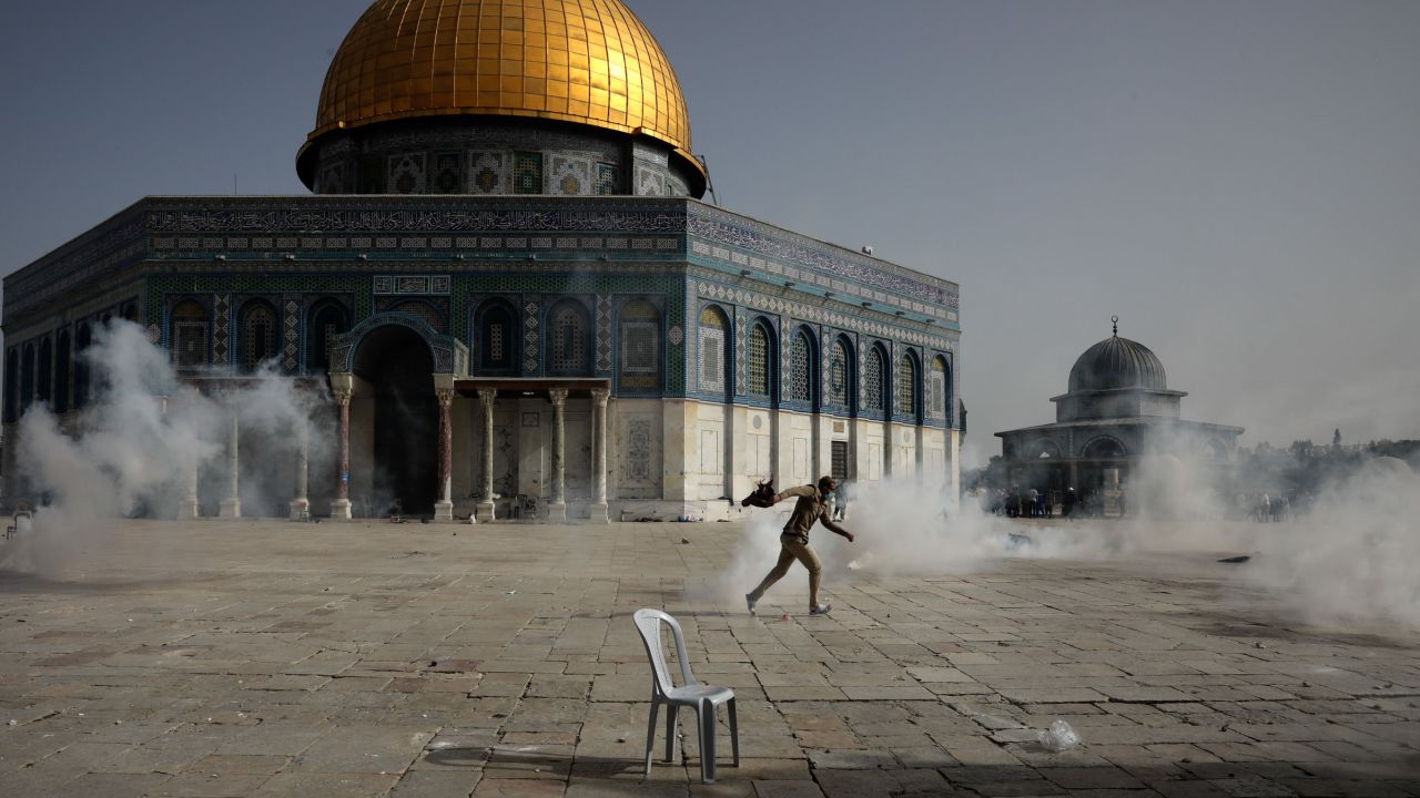 A Palestinian man runs from tear gas during clashes with Israeli security forces at the Al Aqsa Mosque.