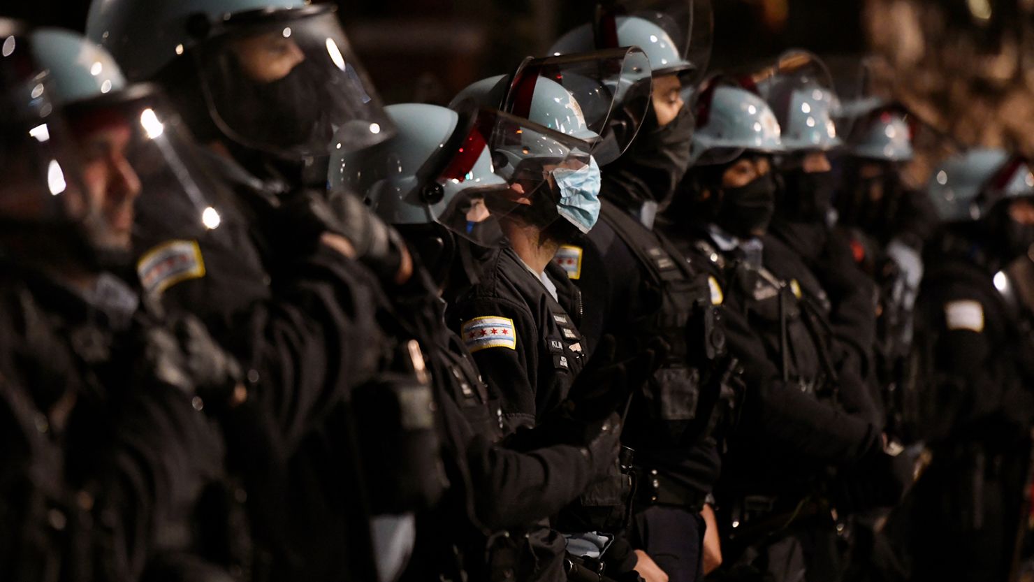 Chicago Police officers look on as people protest the fatal shooting of 13-year-old Adam Toledo by a Chicago Police officer.