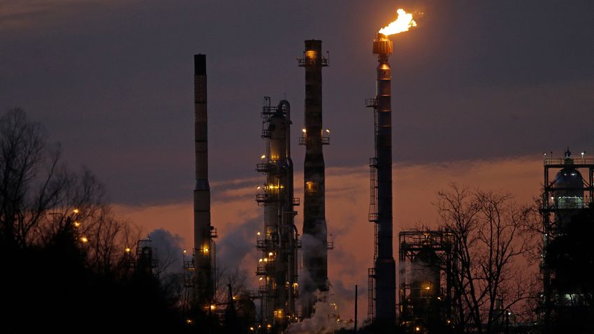 FILE - In this Feb. 13, 2015 file photo, stacks and burn-off from the ExxonMobil refinery are seen at dusk in St. Bernard Parish, La. New York City officials say they will begin the process of dumping about $5 billion in pension fund investments in fossil fuel companies, including Exxon Mobil, because of environmental concerns. (AP Photo/Gerald Herbert, File)