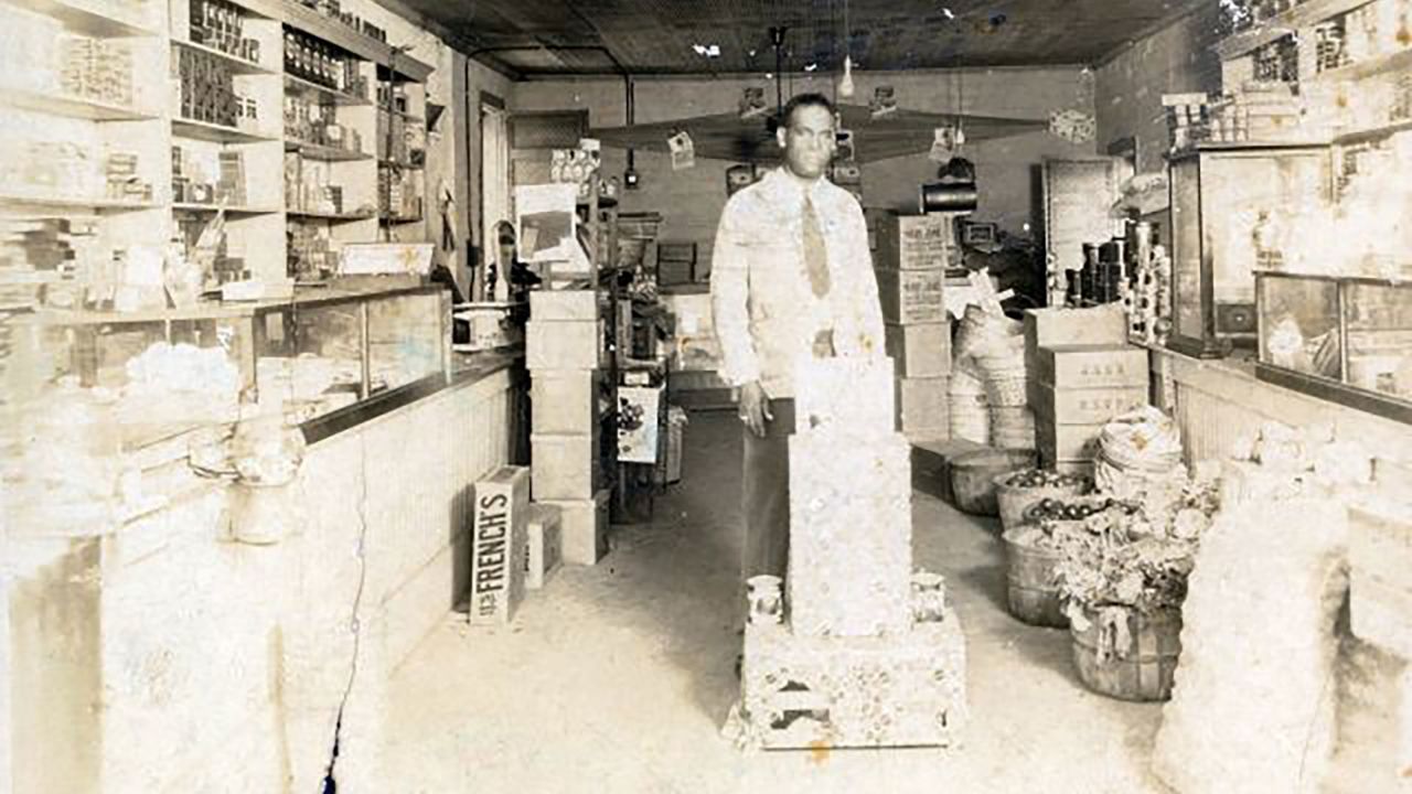 <strong>John D. Mann</strong> and his brothers, McKinley and <a href="https://www.neh.gov/article/1921-tulsa-massacre" target="_blank" target="_blank">O. B. Mann</a>, were well-known grocers in the Greenwood District. J.D. is pictured here in the store he owned on North Greenwood Avenue. According to the Tulsa Historical Society, the store was destroyed in the 1921 race massacre.