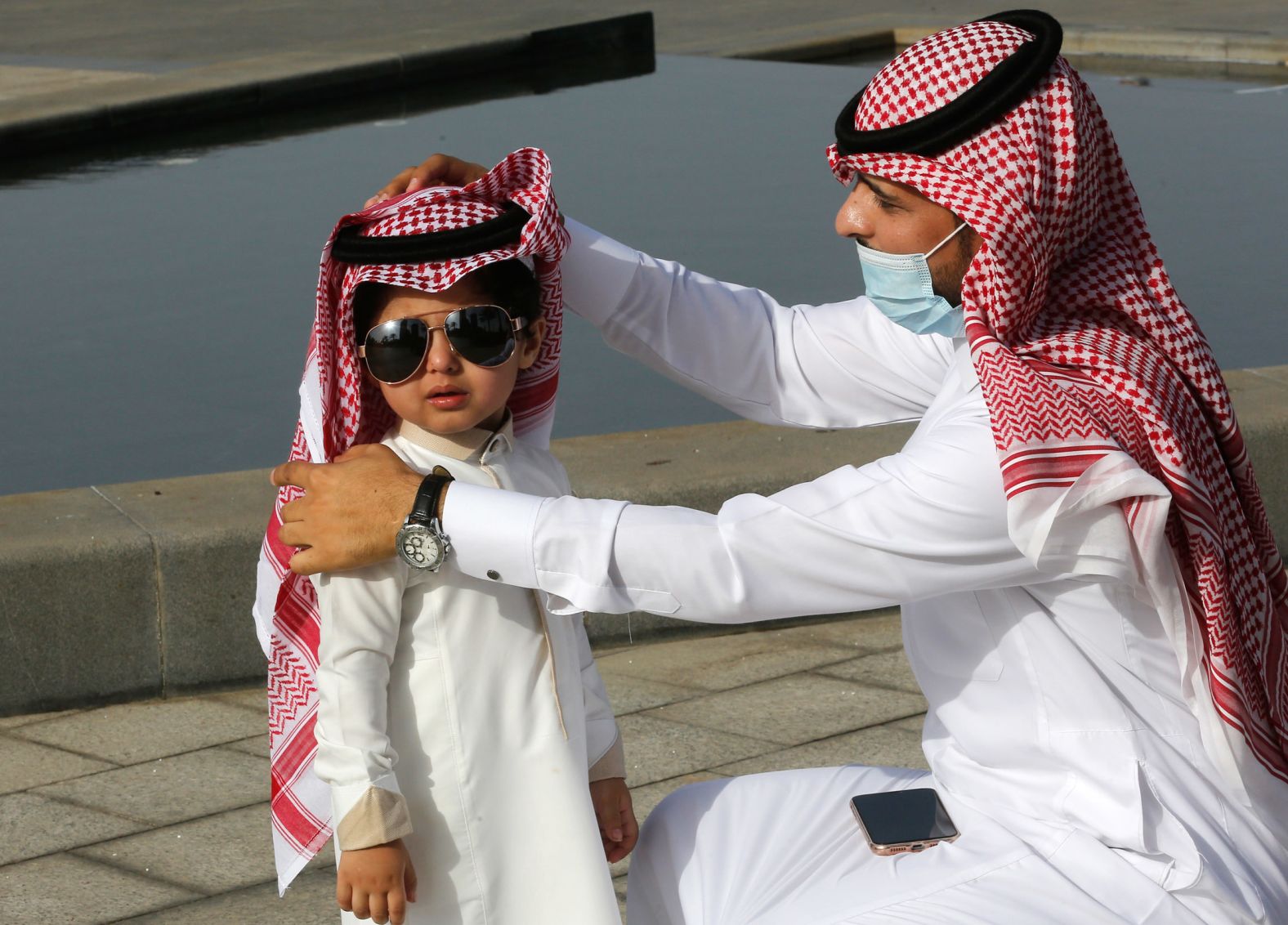 A man arranges his son's traditional head covering after Eid al-Fitr prayers in Jiddah, Saudi Arabia, on May 13.