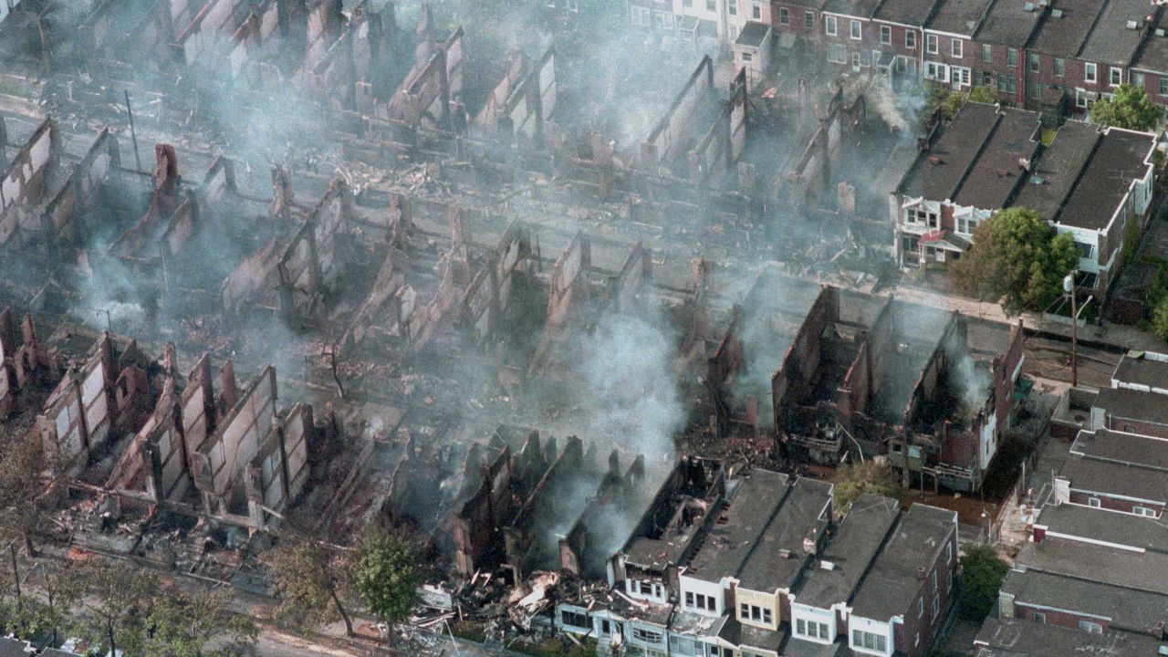 Smoke rises from the smoldering rubble of 61 homes destroyed by fire after a shootout and bombing at the black liberation group MOVE's house in West Philadelphia while police were attempting to force the group's eviction in May 1985.