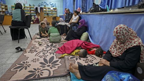 Palestinian families take shelter in a UN school in Gaza City on May 13, 2021, after fleeing from their homes in the town of Beit Lahia. 
