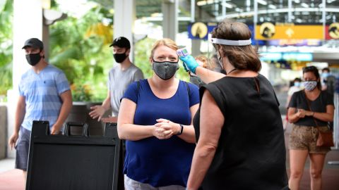 A Universal Studios Orlando employee takes the temperature of a guest last year, on the property's first day of reopening during the pandemic.