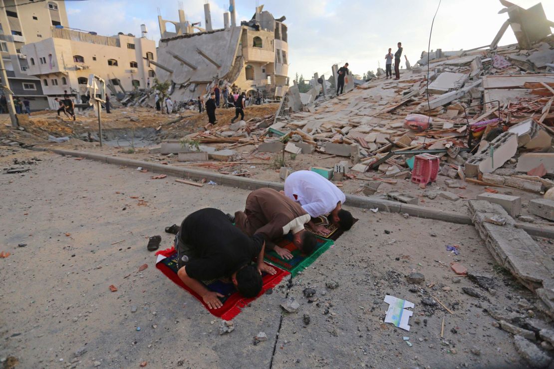 Palestinians perform Eid al-Fitr prayers near buildings destroyed by ongoing Israeli airstrikes in Beit Lahia, Gaza, on May 13.
