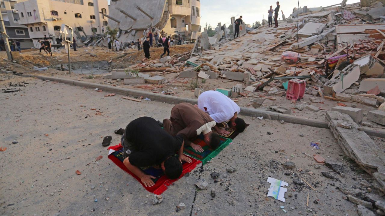 Palestinians perform Eid al-Fitr prayers near buildings destroyed by ongoing Israeli airstrikes in Beit Lahia, Gaza, on May 13.