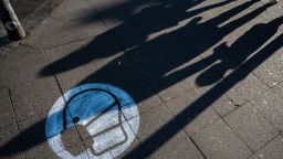 Shadows are projected onto a sign painted on the sidewalk indicating use of face masks is mandatory at a busy crossing in Berlin on March 10, 2021, amid a Coronavirus (Covid-19 pandemic). (Photo by John MACDOUGALL / AFP) (Photo by JOHN MACDOUGALL/AFP via Getty Images)