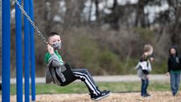 LOUISVILLE, KY - MARCH 17: A child uses a swingset while others play nearby during socially distanced recess on the playground of Medora Elementary School on March 17, 2021 in Louisville, Kentucky. Today marks the reopening of Jefferson County Public Schools for in-person learning with new COVID-19 procedures in place. (Photo by Jon Cherry/Getty Images)