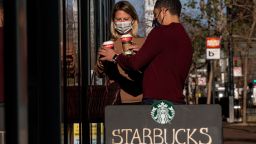 People wearing protective masks hold beverages outside a Starbucks coffee shop in San Francisco, California, U.S., on Thursday, Jan. 21, 2021. Starbucks Corp. is expected to release earnings figures on January 26. Photographer: David Paul Morris/Bloomberg via Getty Images