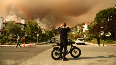 A man takes a photo of the plume of smoke created by the Palisades fire in Topanga State Park on May 15, 2021