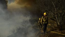 Los Angeles Fire Department firefighters wait for water pressure  to extinguish the flames from the Palisades fire in Topanga State Park, North West of Los Angeles on May 15, 2021.