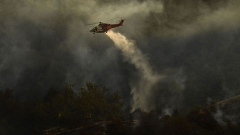 Firefighters keep a lookout as a Los Angeles Fire Department helicopter makes a water drop Saturday on the Palisades Fire in Topanga State Park.