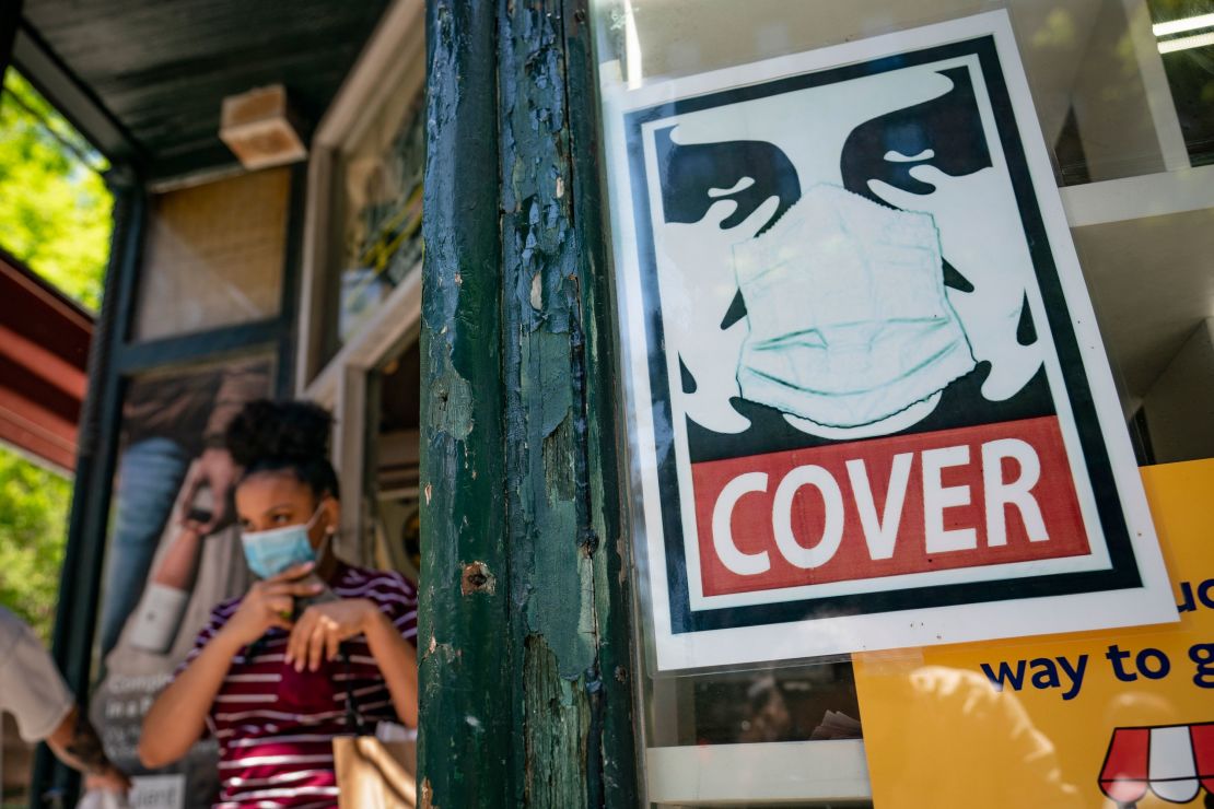 A customer exits a corner market while wearing a mask in the retail shopping district of the SoHo neighborhood of the Manhattan borough of New York on May 14, 2021