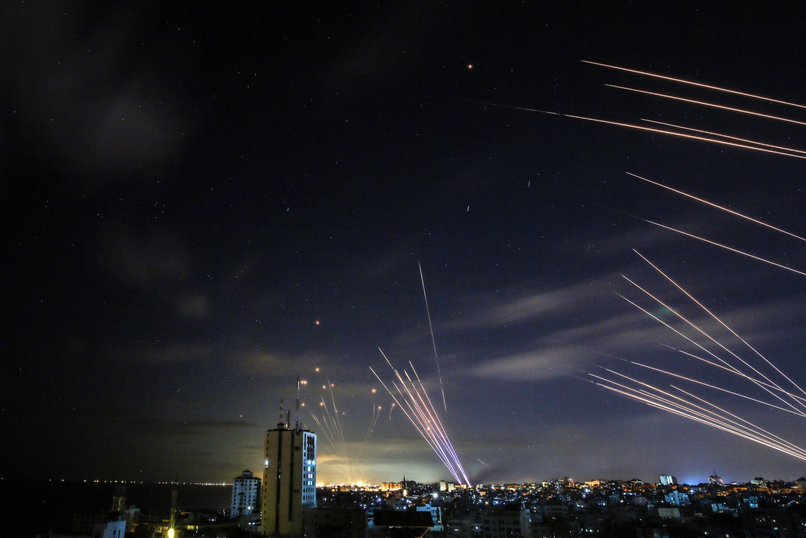 In the background, the Israeli Iron Dome aerial-defense system intercepts rockets fired by Hamas militants toward southern Israel on May 16.