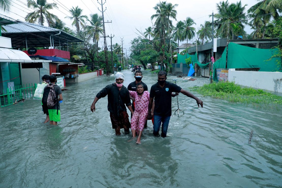 Police and rescue personnel evacuate a local resident through a flooded street in a coastal area in Kochi on May 14.