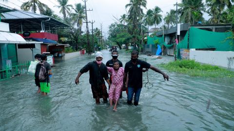 Police and rescue personnel evacuate a local resident through a flooded street in a coastal area in Kochi on May 14.