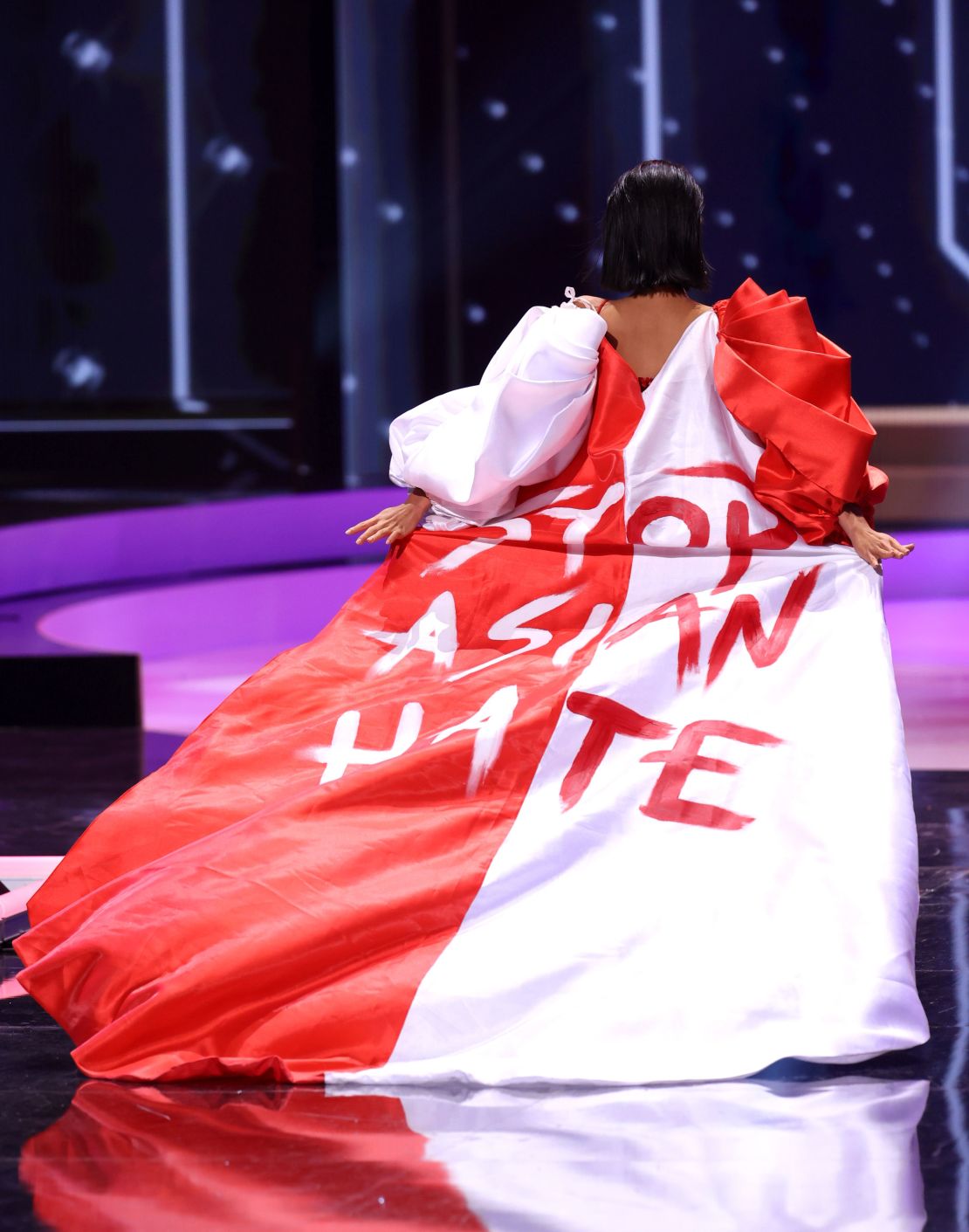 Miss Universe Singapore Bernadette Belle Ong wears a Arwin Meriales x Paulo Pilapil Espinosa cape hand-painted with the hashtag "#StopAsianHate." 