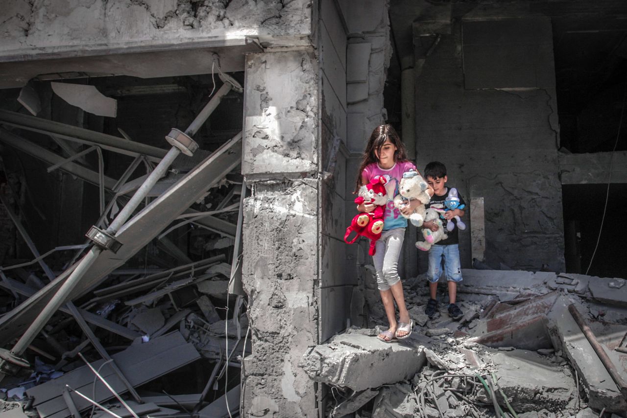 Children salvage toys from their home at Gaza City's Al-Jawhara Tower, which was heavily damaged in Israeli airstrikes.
