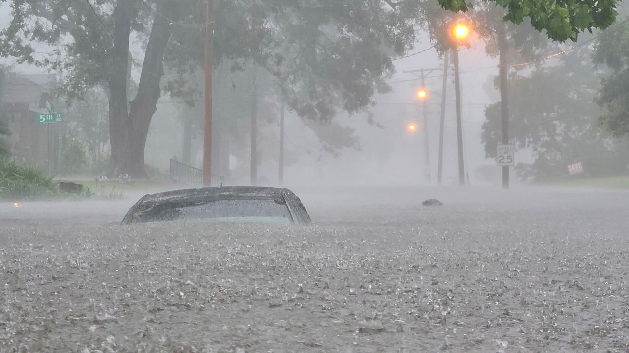 The car nearly disappears in the flooded street.