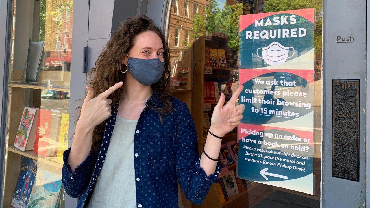 Colleen Callery, marketing director at Books are Magic in Brooklyn, stood next to the store's "masks required sign," which will remain despite the CDC change in mask guidance last week.