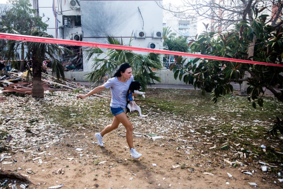 A woman in Ashdod, Israel, carries her dog and runs for shelter after sirens warned of rockets fired from Gaza. It was near the site where a previous rocket hit.